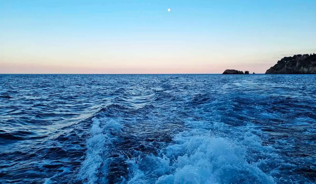 Boat anchored in a hidden bay during a Taormina sunset cruise